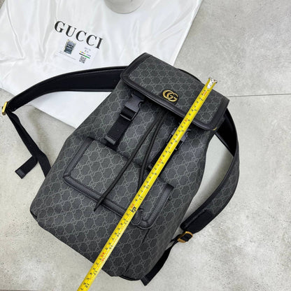 Dark gray GG monogram backpack with front flap, buckle straps, and top handle