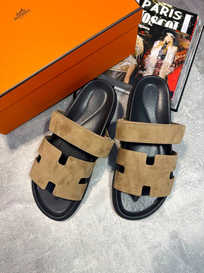 Tan suede slide sandals with black cutout strap and cushioned footbed, pair