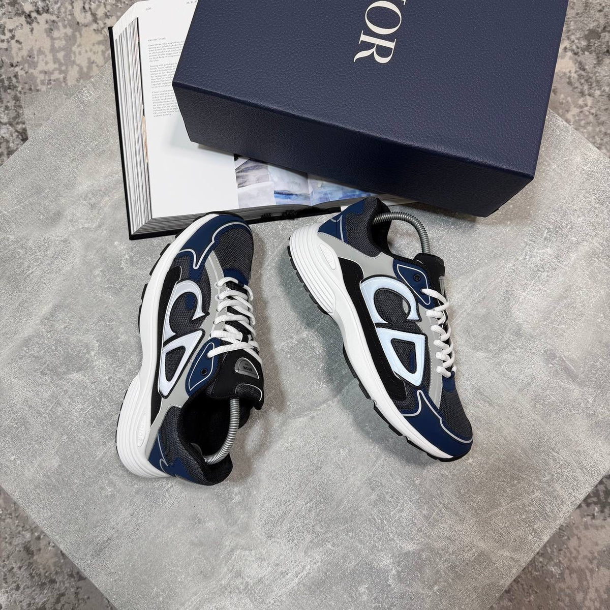 White lace-up stealth sneakers with navy overlays, black tongue, and chunky rubber sole