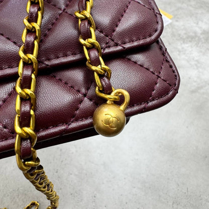Burgundy quilted leather flap bag with gold-tone chain and CC charm