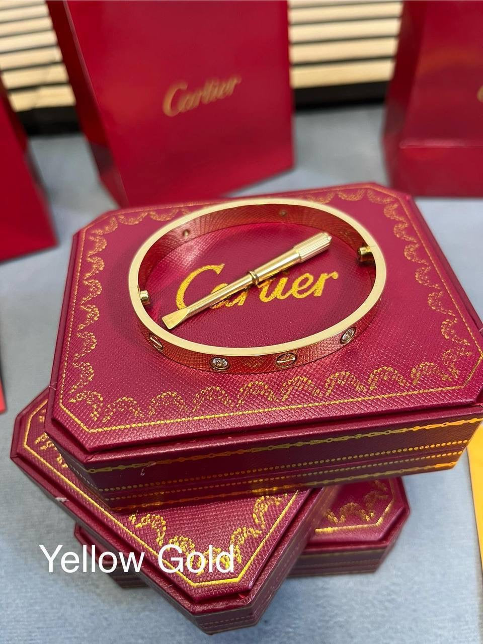 Yellow gold love bracelet with Cartier bar detail on red Cartier gift box