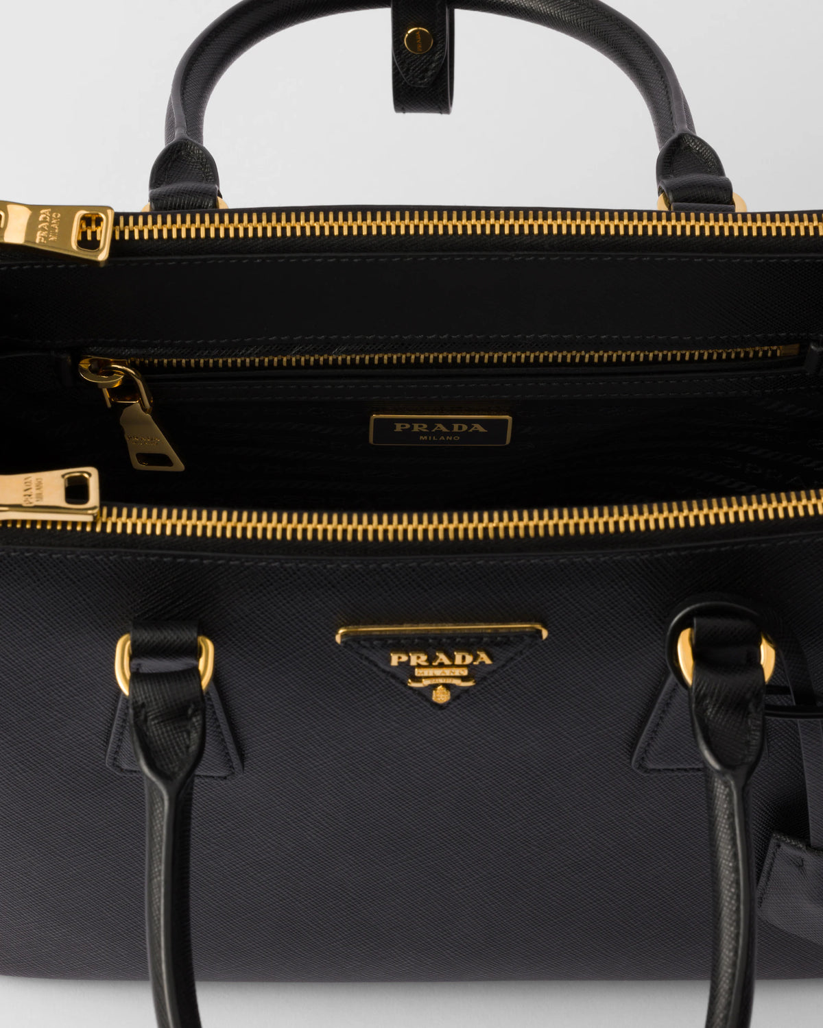 Close-up of black Galleria bag showing zipper track, interior, and Prada logo plate