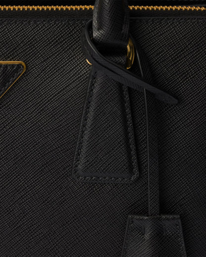 Close-up of black Saffiano bag tassel pulls and gold zipper trim on the front