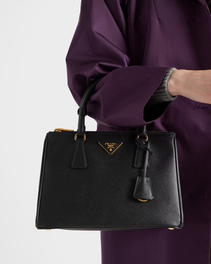 Black Galleria medium Saffiano leather bag held in hand with gold zipper and logo