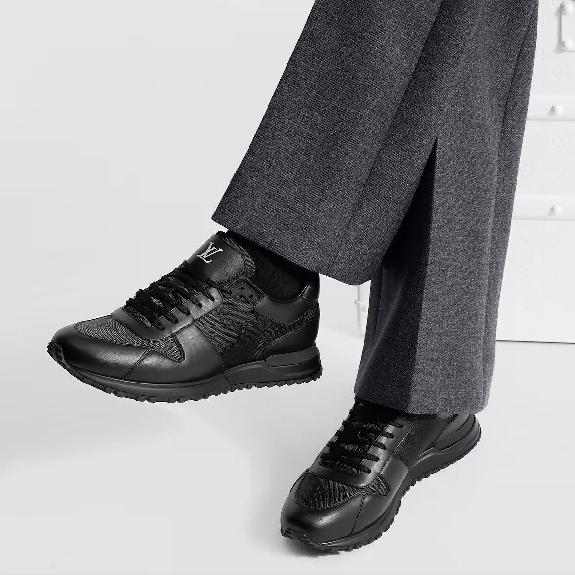 Run Away Sneaker on feet, black lace-up with dark monogram-style overlays
