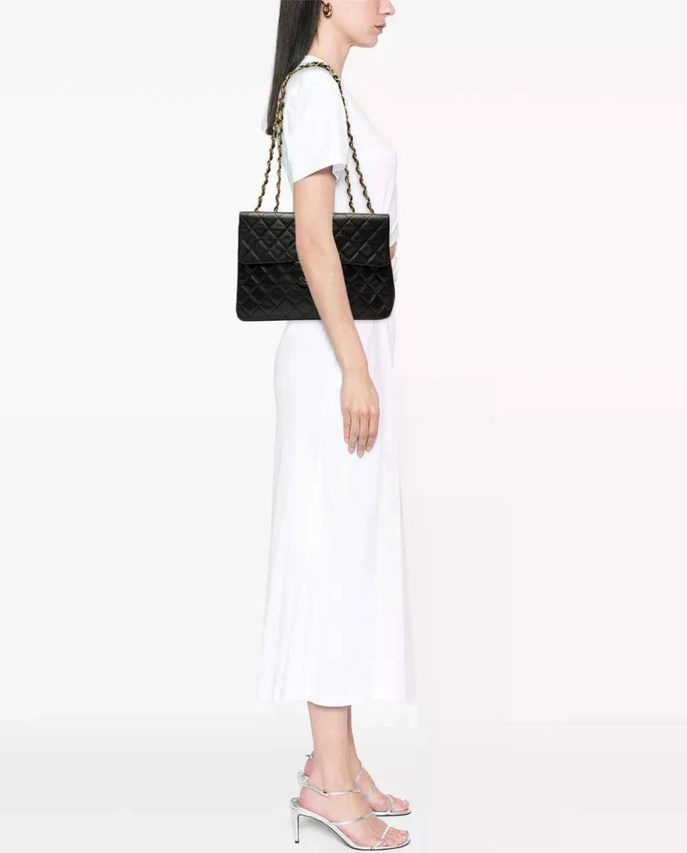 Maxi Classic Flap bag on model’s shoulder; black quilted design with gold chain strap