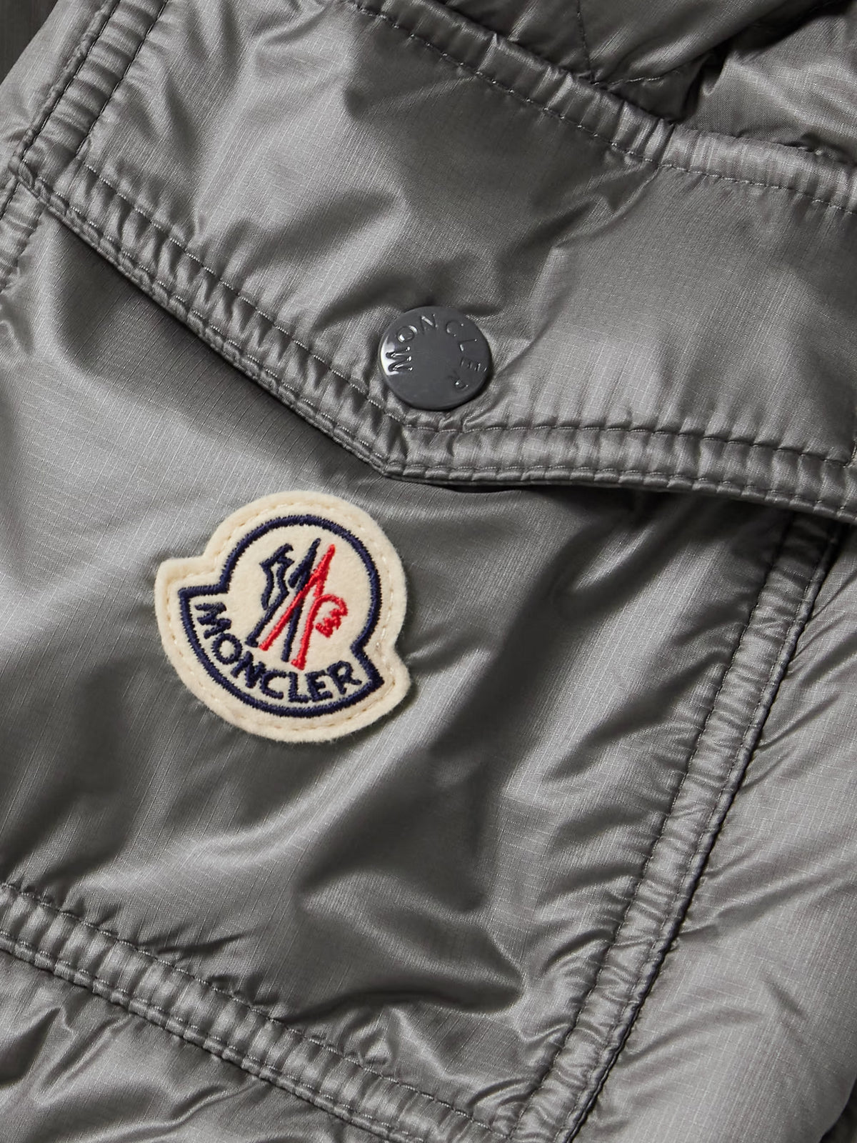 Gray down jacket fabric close-up with MONCLER patch