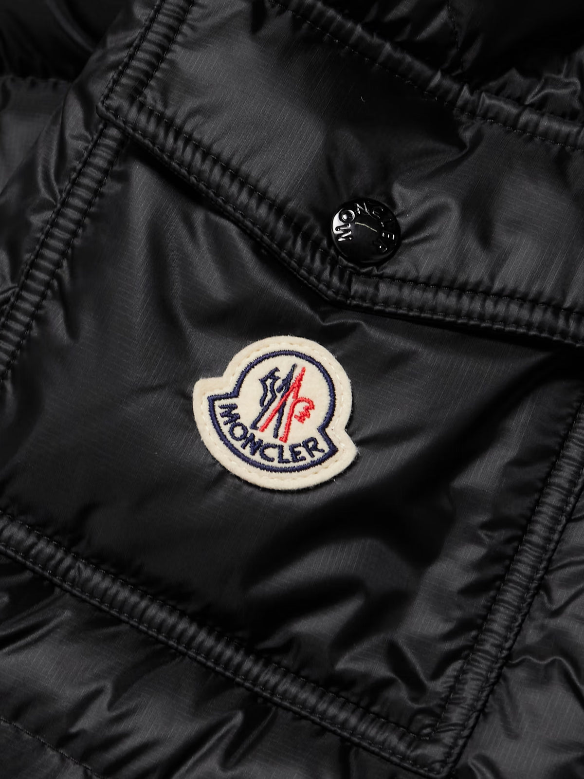 Black down jacket fabric close-up with MONCLER patch