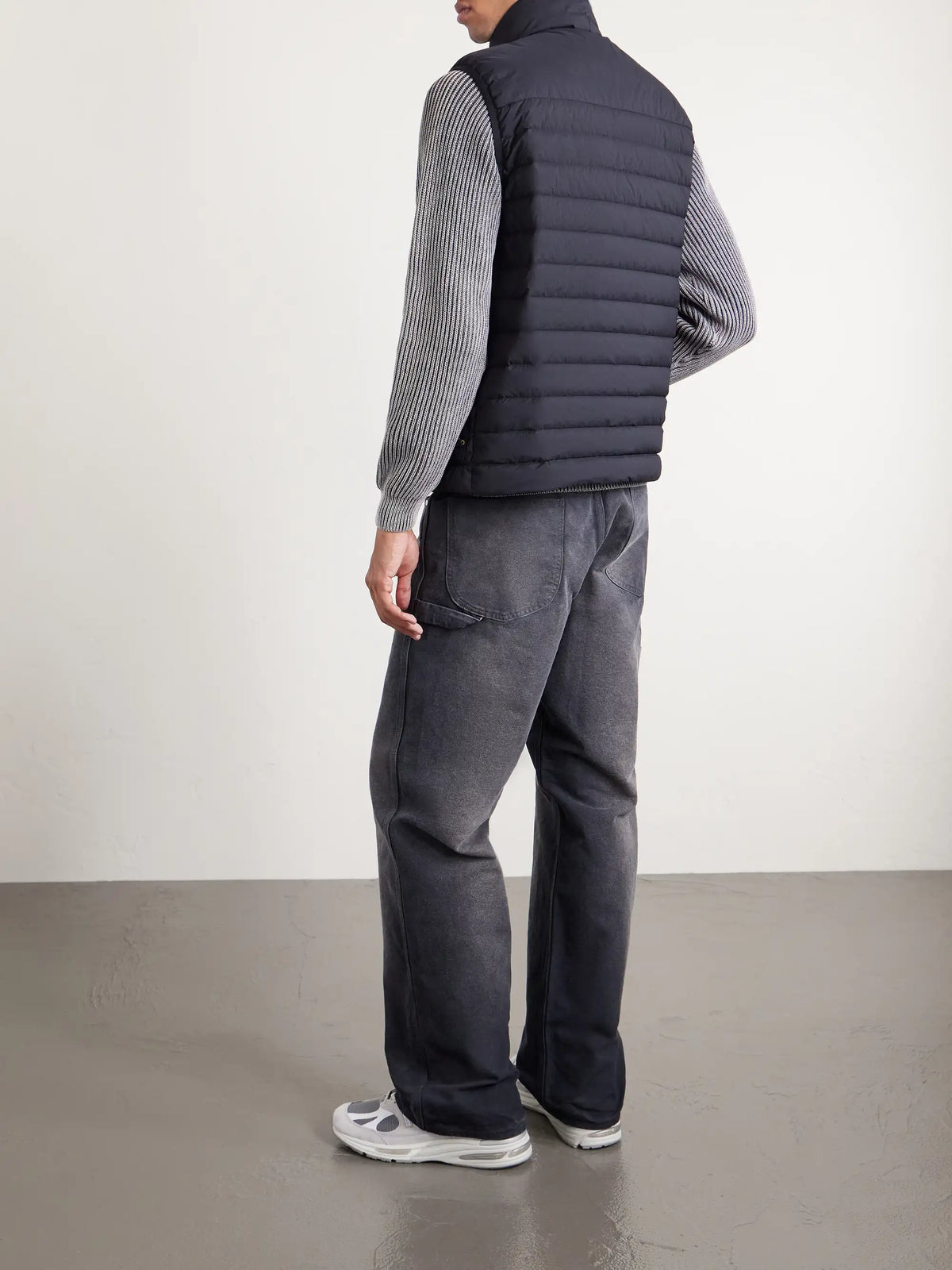 Side view of black quilted down gilet with ribbed knit sleeves