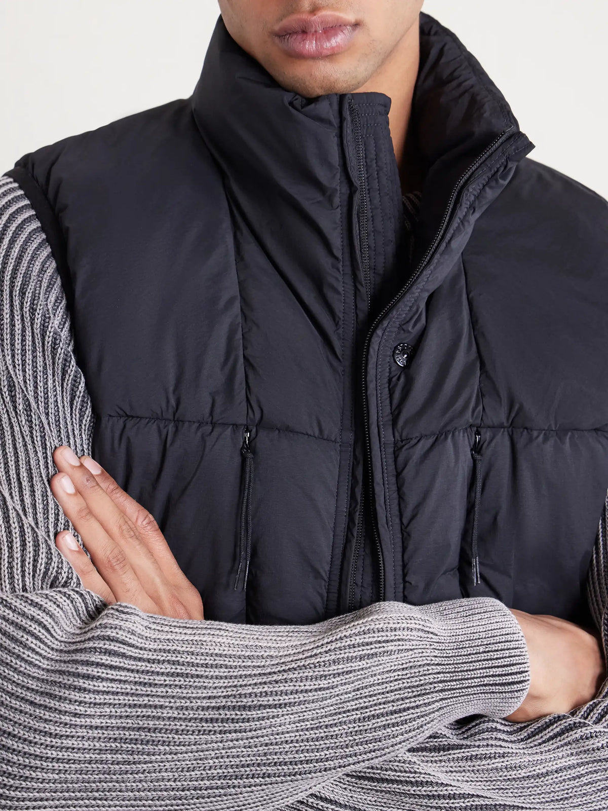 Close-up: black down gilet with stand collar, zip front and drawstring pulls