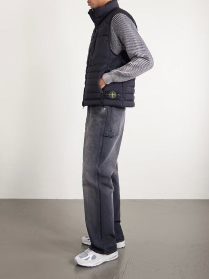 Black quilted down gilet with side pockets, worn with striped sleeves