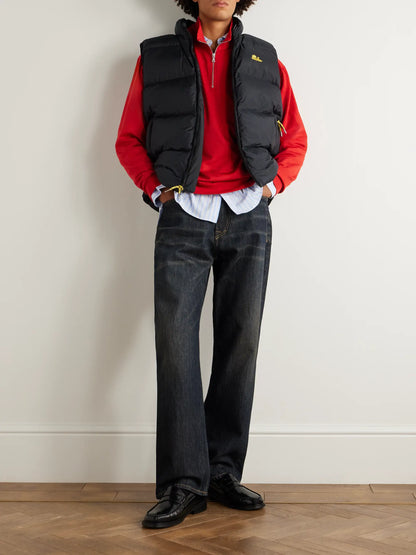 Black quilted logo vest worn over a red hoodie; sleeveless puffer styling